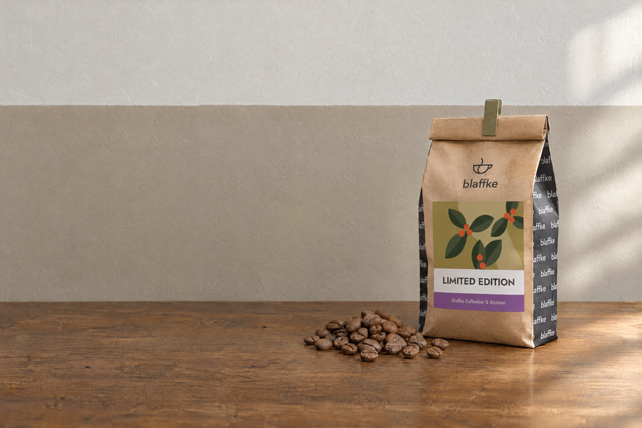 Kraftpapiertüte der Kenia Limited Edition von Blaffke, oben umgeschlagen und mit einer Klammer verschlossen, daneben Kaffeebohnen auf einem Holztisch